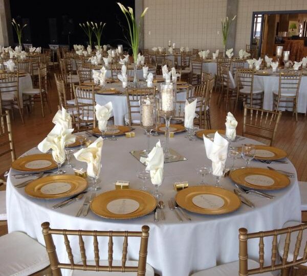 Fine china, linens, stemware and flatware with gold Chiavari Chairs at Sanders Beach.