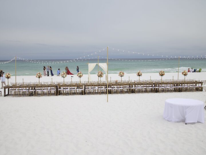 Long banquet table set for a reception on the white sand beach