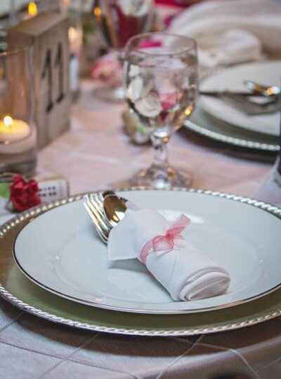 place settings Silver charger white plate white napkin rolled silverware coral accents