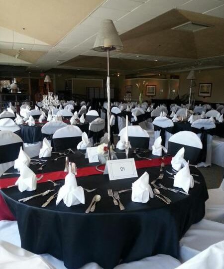Table setting — Black and red table linens with white chair covers.